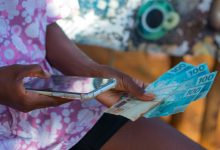 Mulher com celular na mão ganhando dinheiro.