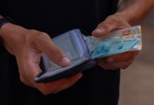 Homem guardando dinheiro na carteira.