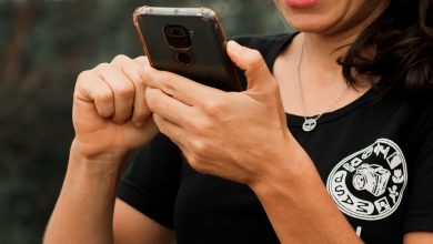 Mulher meia idade sorrindo com o celular na mão.